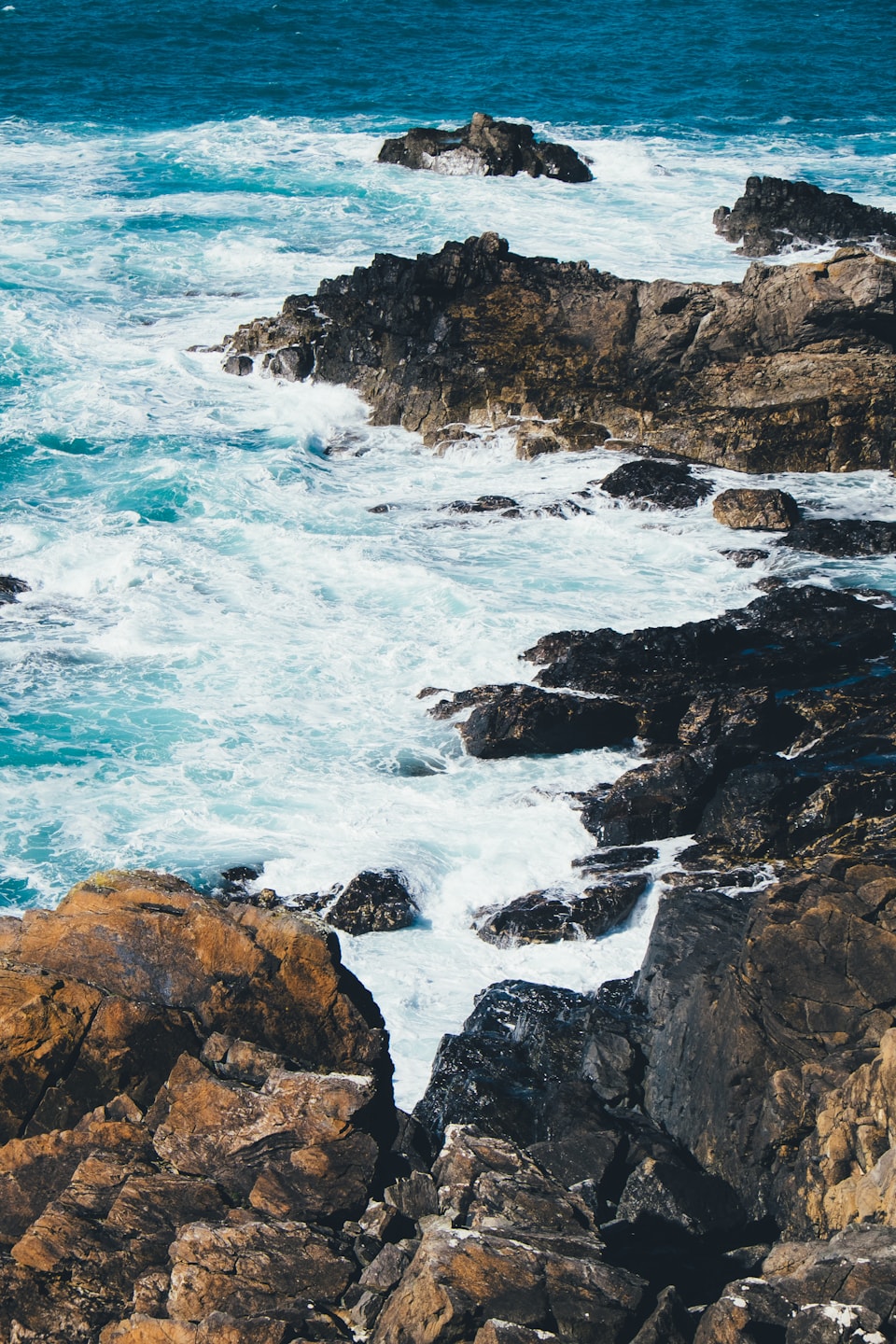 White waves washing around dark coastal rocks